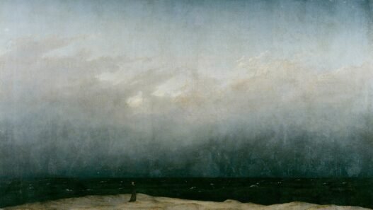 A tiny figure in a dark robe stands alone on a pale strip of dune beside a dark sea, under a vast grey sky that fills most of the painting.