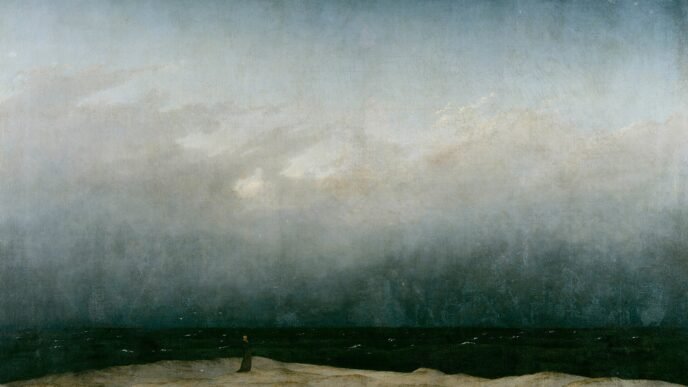 A tiny figure in a dark robe stands alone on a pale strip of dune beside a dark sea, under a vast grey sky that fills most of the painting.